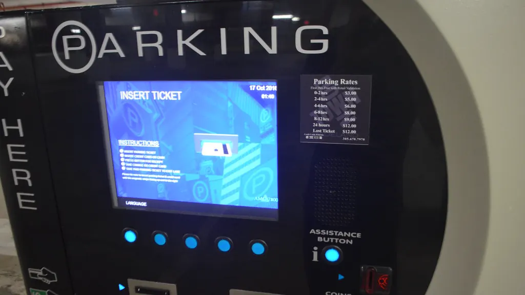A parking pay station screen reading “insert ticket”, with the rate card beside it