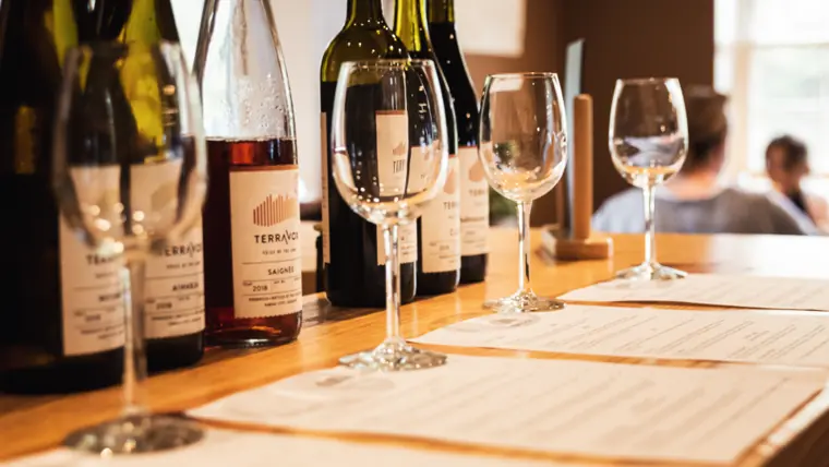 A restaurant table laid with wine glasses and bottles in warm evening light